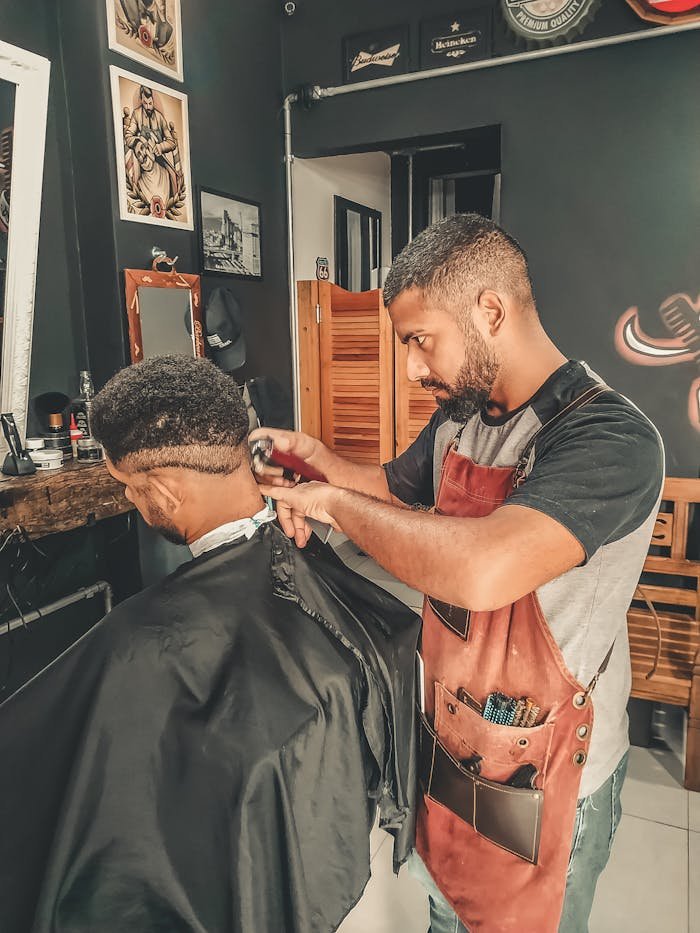 Peluqueria Xerica en Carlet. Experienced barber styling hair in a modern barbershop setting.