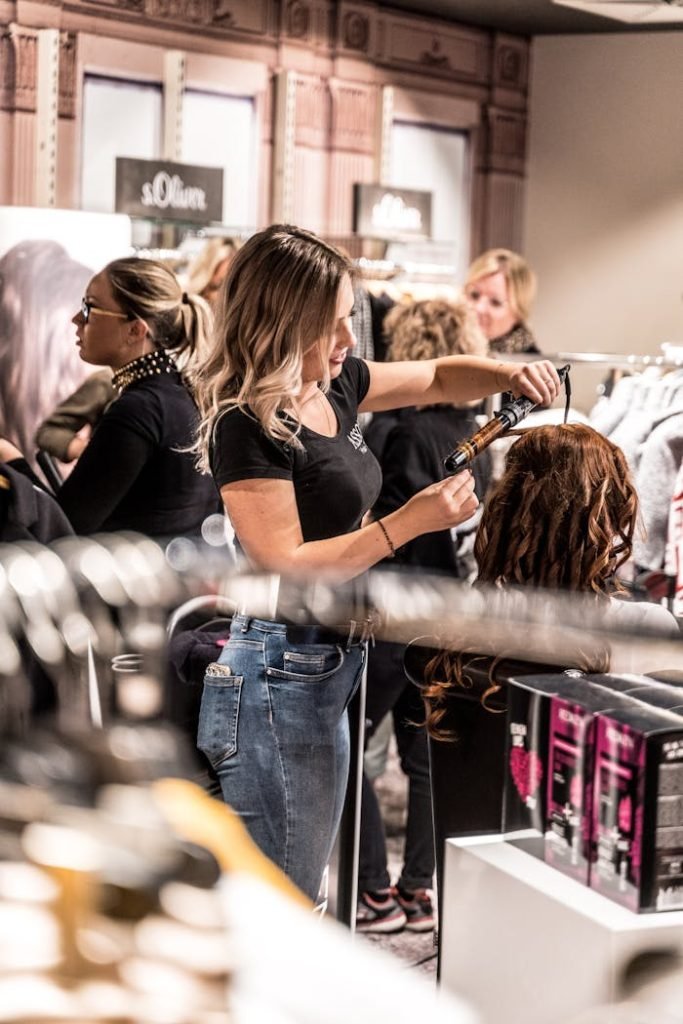 Peluqueria Xerica en Carlet. A skilled hairstylist uses a curling iron to style a clients hair in a busy salon.